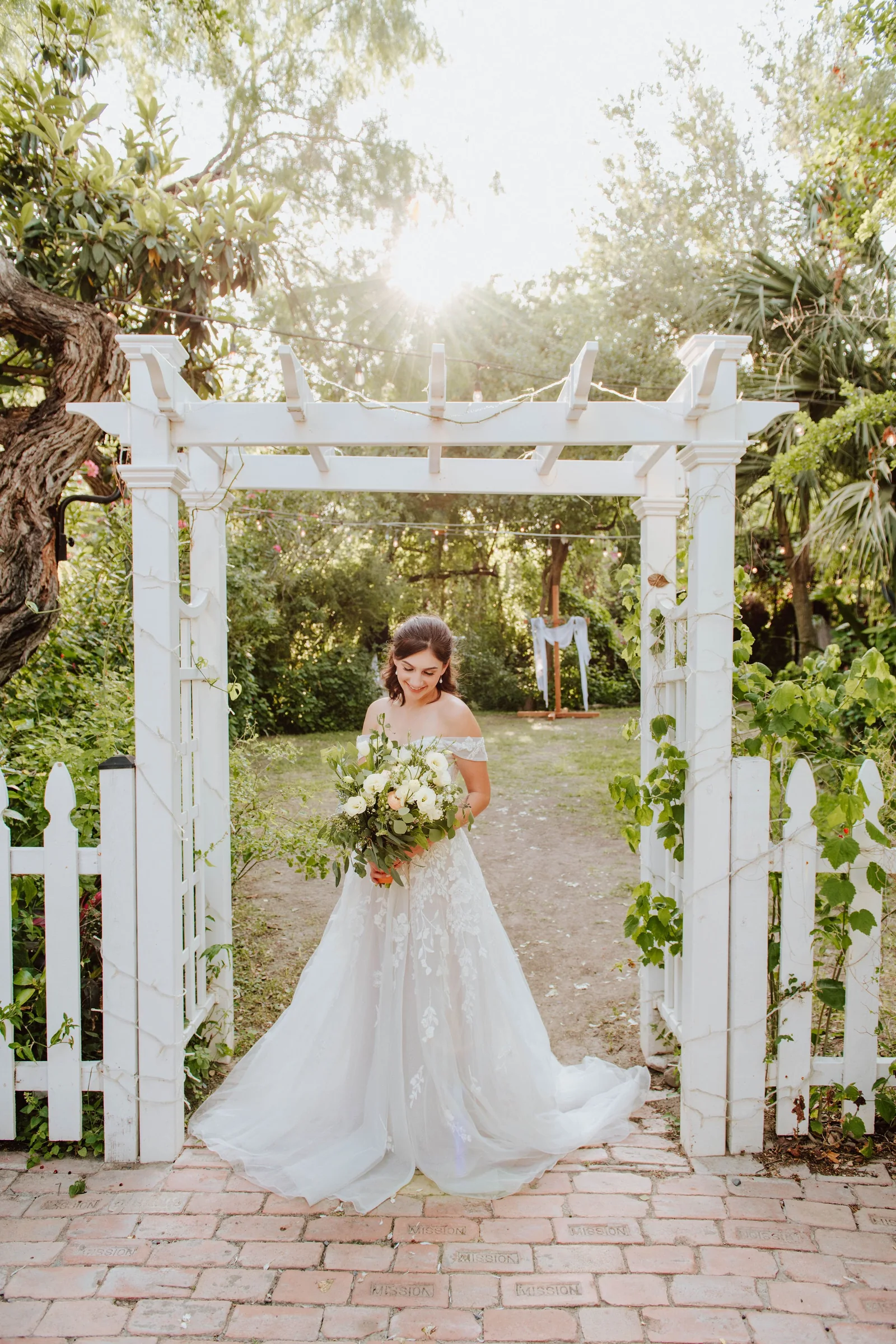 Flower girl standing beneath the outdoor ceremony arbor
